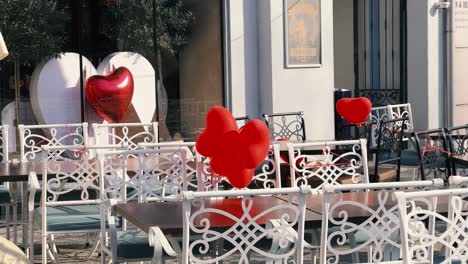 Four-red-heart-shaped-balloons-blown-by-the-strong-wind-on-the-main-pedestrian-street-in-the-city-of-Plovdiv,-Bulgaria