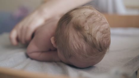 newborn boy lies on stomach and enjoys legs massage