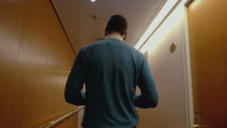 Man walking along the hotel corridor back to the camera