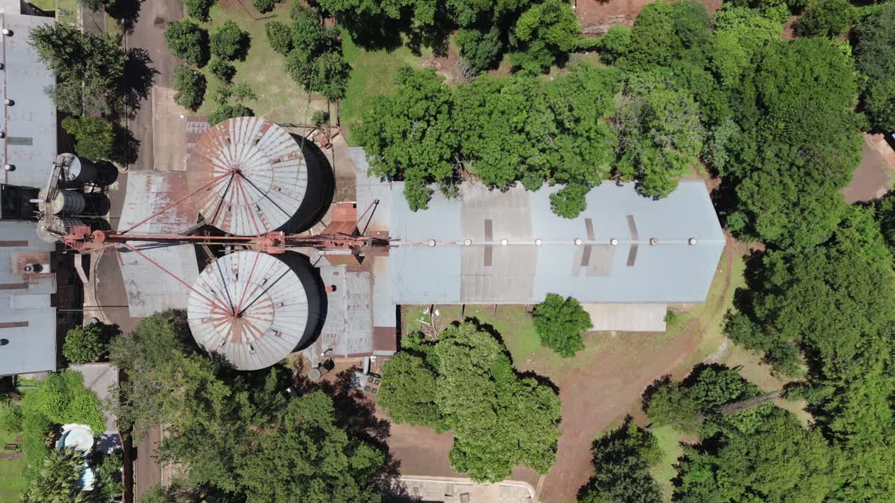 나무로 둘러싸인 곡물 공장과 저장 시설의 위에서 아래로 보입니다.