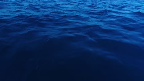 basso angolo, profondo modello di texture dell'acqua dell'oceano blu con ondulazioni superficiali che definiscono il sole, aerea