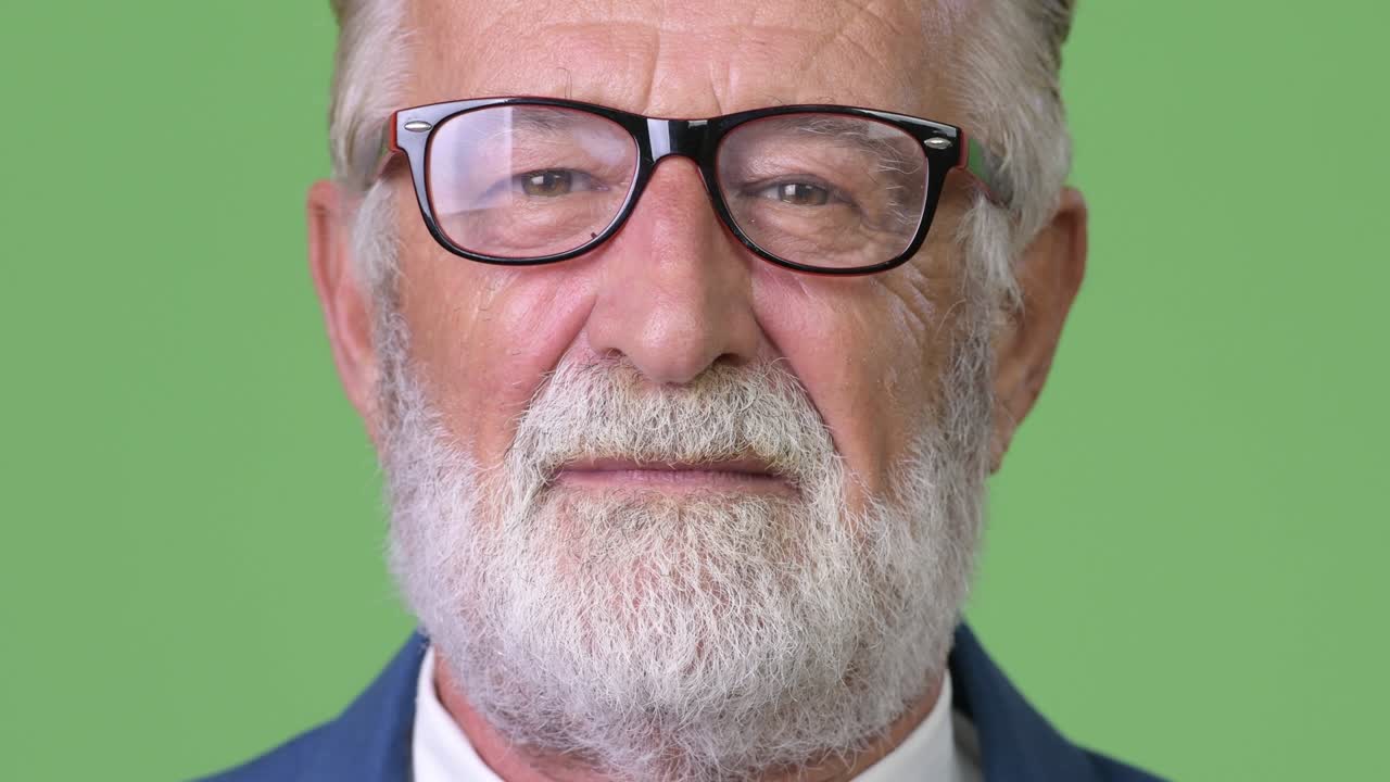 hombre de negocios barbudo y guapo contra un fondo verde.