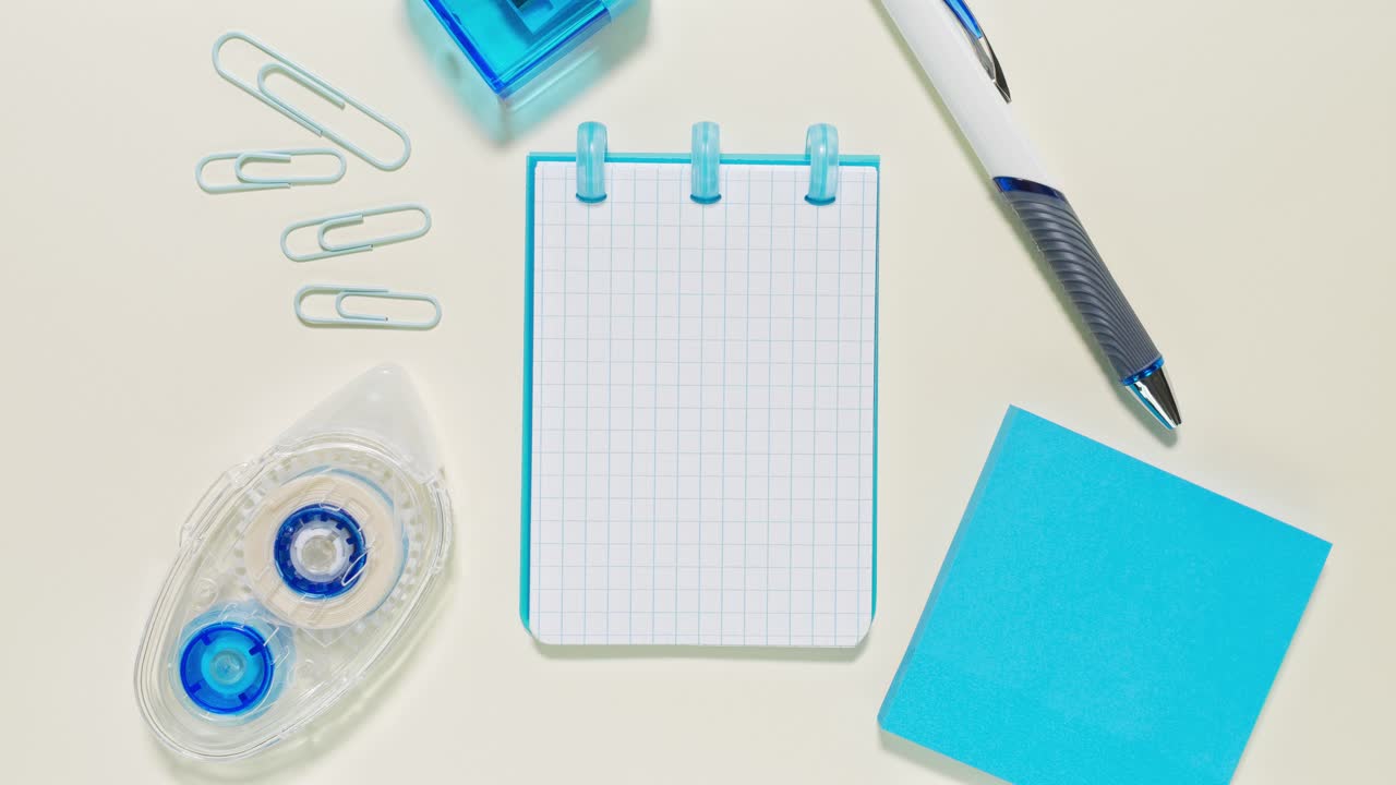 Overhead stop motion of blue stationery framing a grid notepad that serves as copy space
