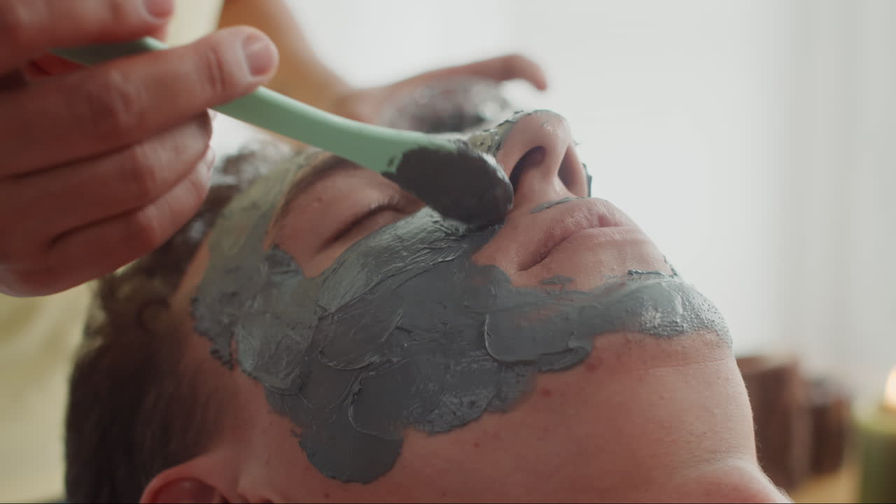 Young Man Relaxing with Clay Mask on Face at Beauty Studio