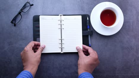 person planning on desk with notebook, glasses and tea