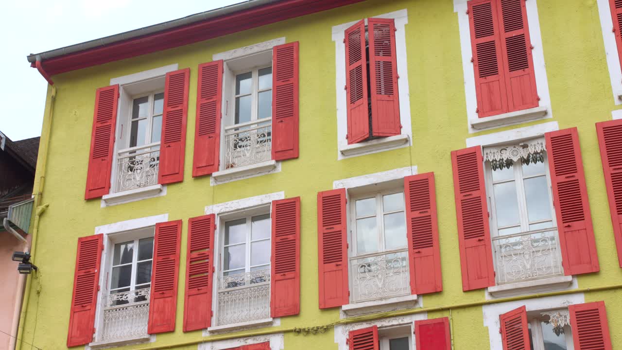 Vibrant building with yellow walls and red shutters in Vizille France on a sunny day