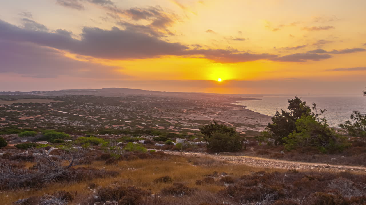 Belo timelapse de paisagem costeira ao pôr do sol, com um céu dourado
