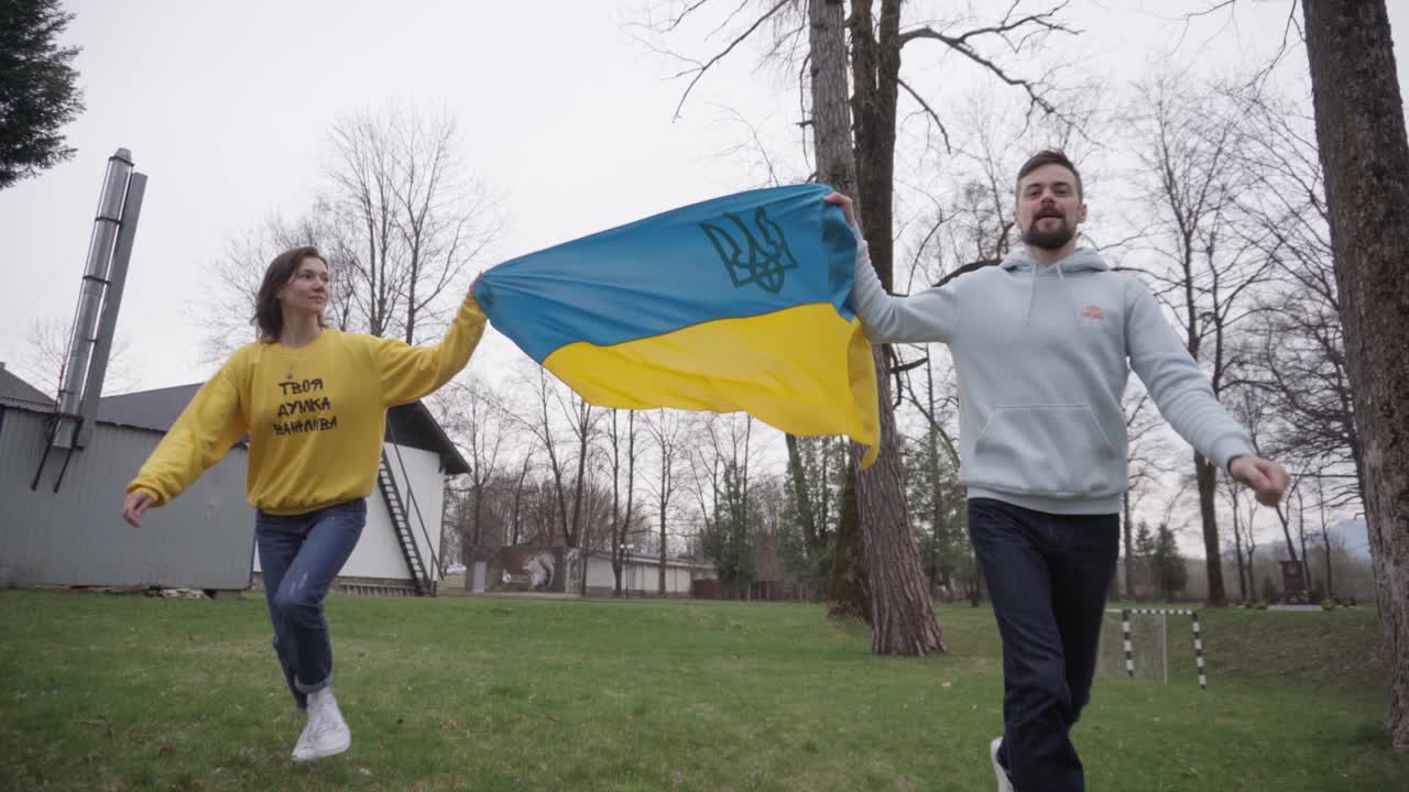 девочка и мальчик держат и ходят с украинским флагом. символ сочувствия. надпись на свитере девушки: "твоё мнение важно"