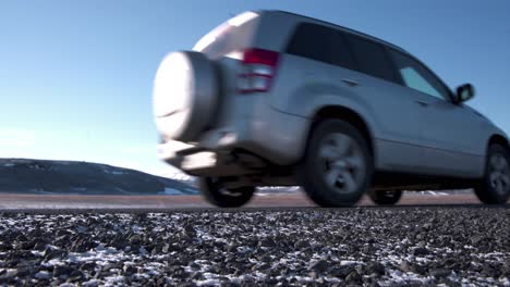 Close-up-of-a-car-driving-on-road-in-a-frozen-mountain-plain,-Iceland