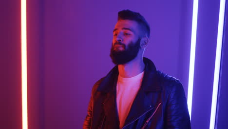 close up view of young man smoking a cigarette on purple neon lights background