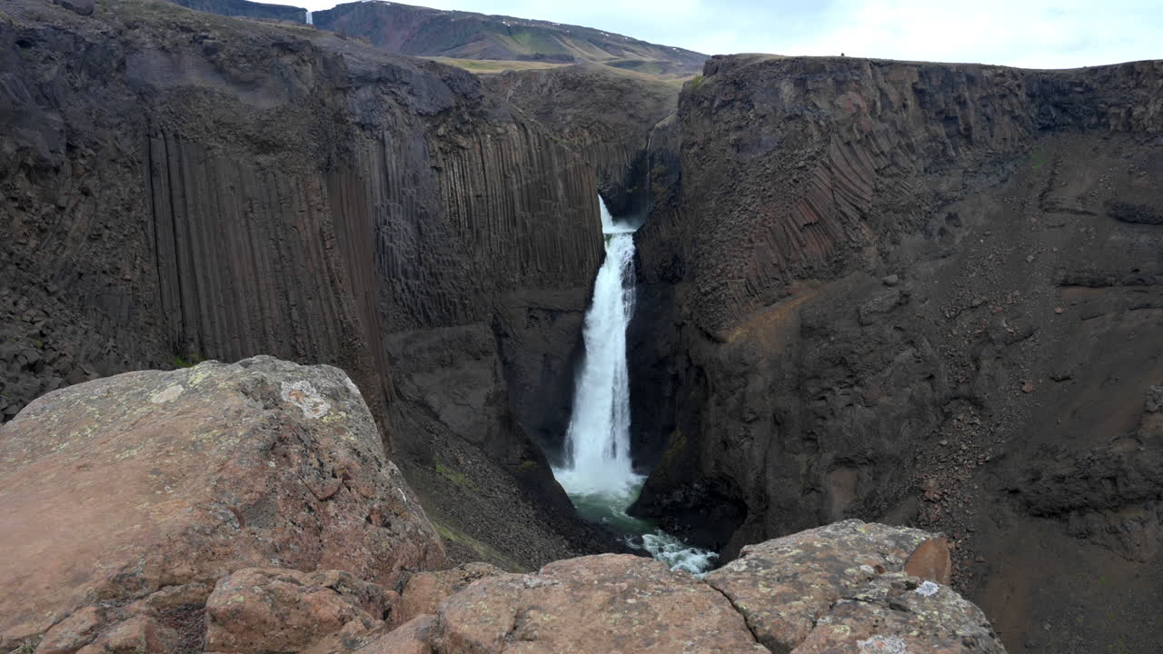 cascada alta entre columnas de basalto gris