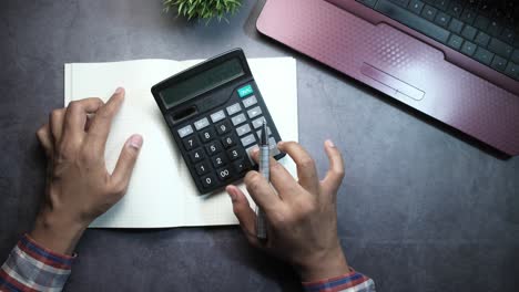 persona que usa una calculadora y un cuaderno en un escritorio