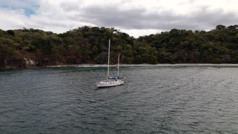 single white sailboat navigating on the tropical coasts of the pacific ocean