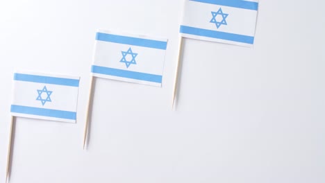 close up of three flags of israel lying on white background with copy space