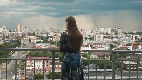 dreamful woman leans on handrail standing on viewing deck