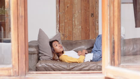 asian young woman relaxing on sofa at home, enjoying peaceful afternoon