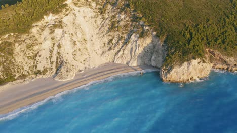 aerial view of beautiful sandy milos beach of lefkada, ionian island, greece. sunset golden sunlight and pristine waves breaking the turquoise blue sea on the shore