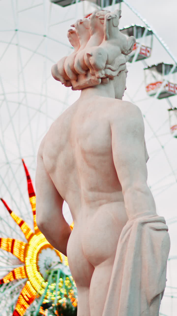 Nice, France - December 8, 2024: Apollo statue in the Fontaine du Soleil at Place Massena with a ferris wheel on the background. Vertical