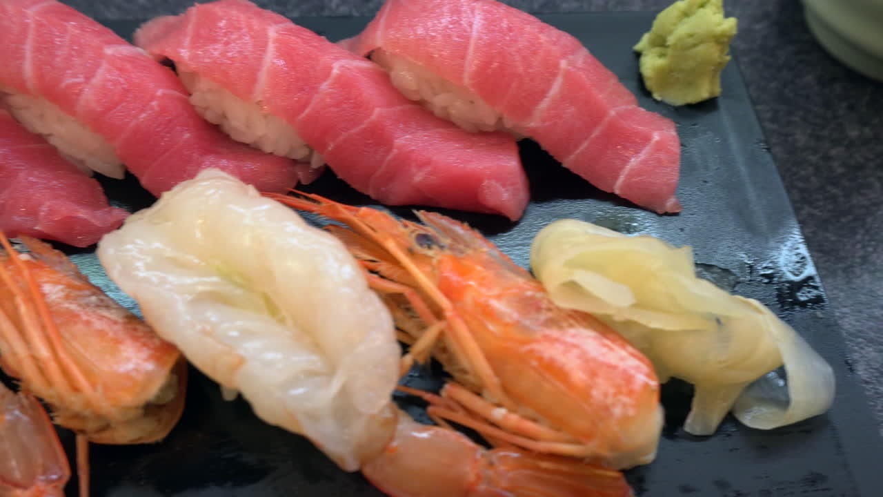 일본 도쿄의 스시 레스토랑에서 먹을 준비가 된 도금된 오토로와 아마에비 스시를 가까이서 볼 수 있습니다.