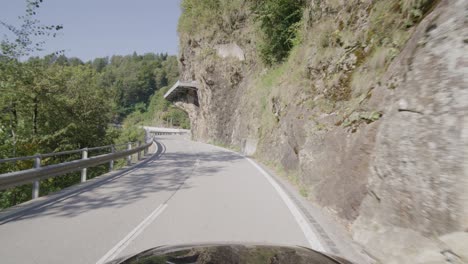 driving on a narrow mountain road in a forest in the italian alps