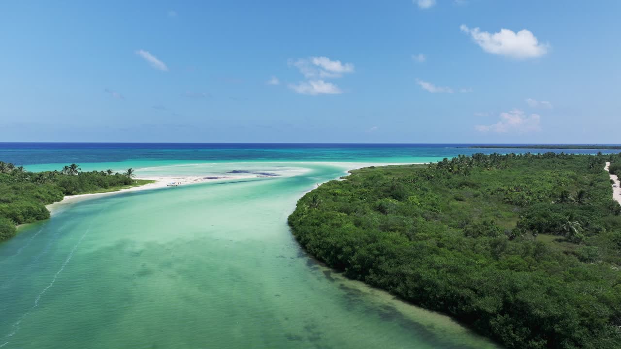 Dolly di drone sopra una passerella su un estuario fluviale sabbioso e un canale che conduce all'acqua blu dell'oceano, Tulum Messico