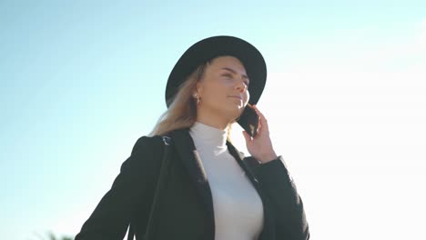 young woman talking on mobile phone on bridge in sunlight