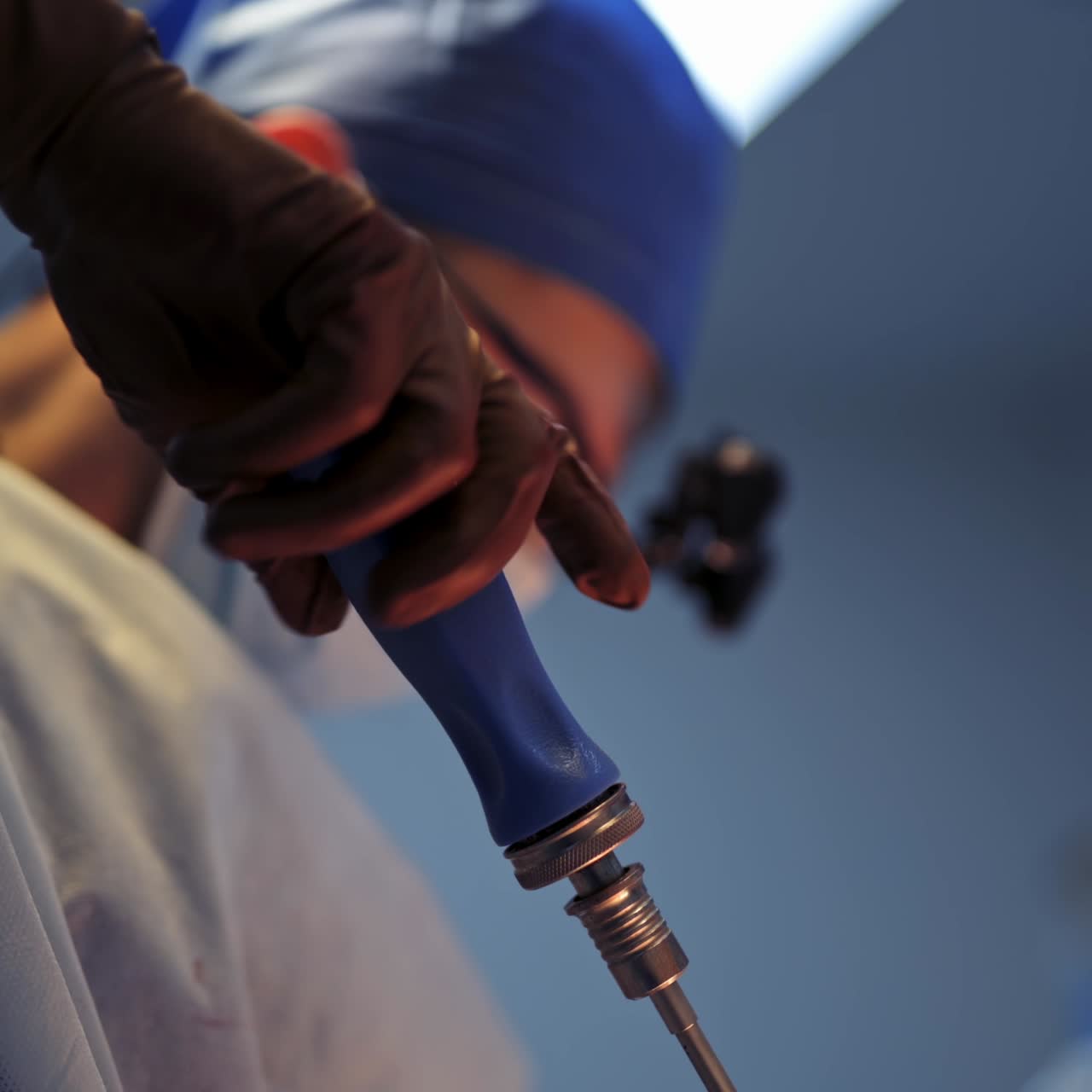 Selective focus on hands of a neurosurgeon with special instrument. Serious professional doctor in operaton room