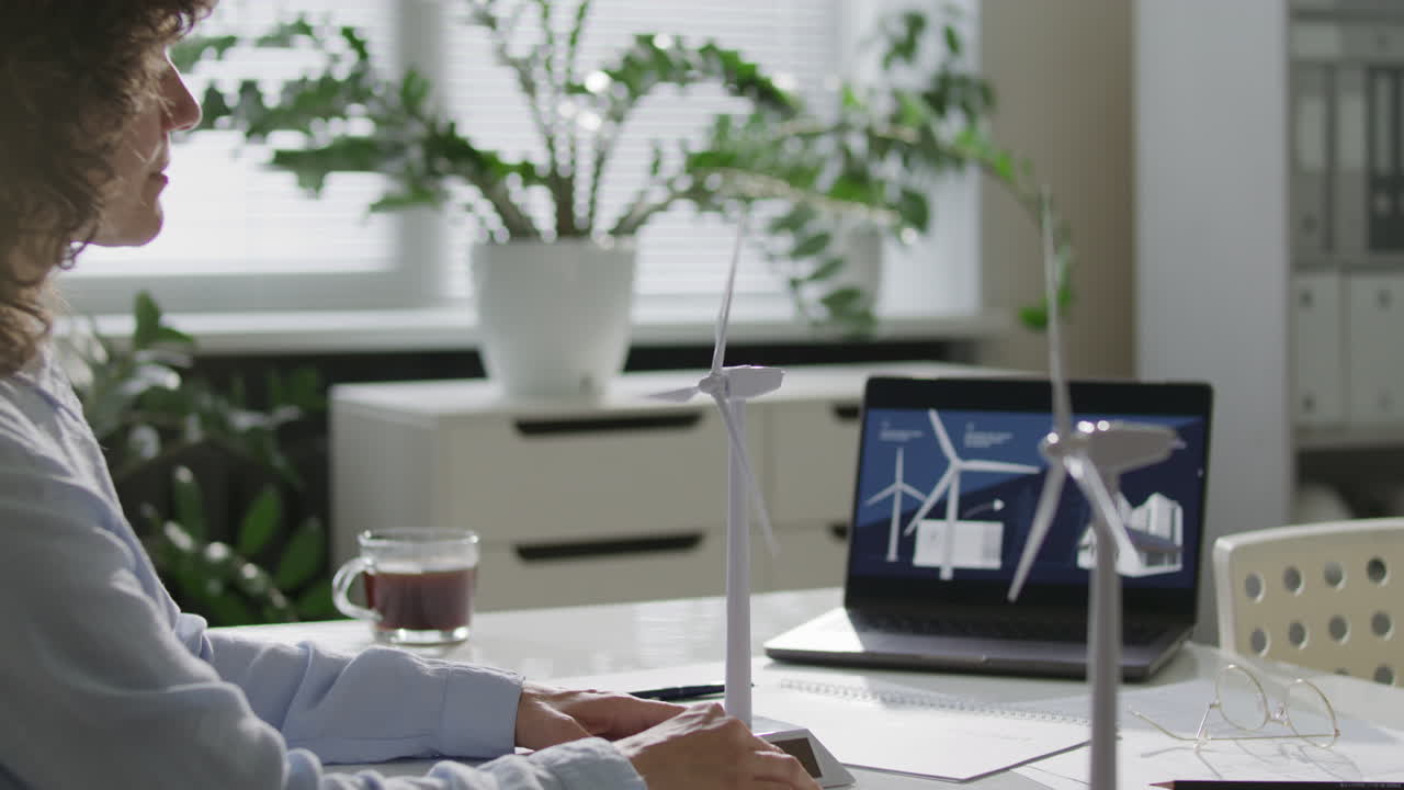 Female Green Energy Engineer Analyzing Wind Turbine Model in Office