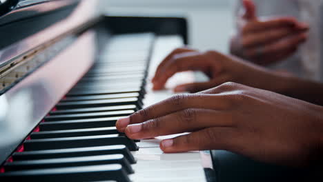 primer plano del alumno con el maestro tocando el piano en la lección de música