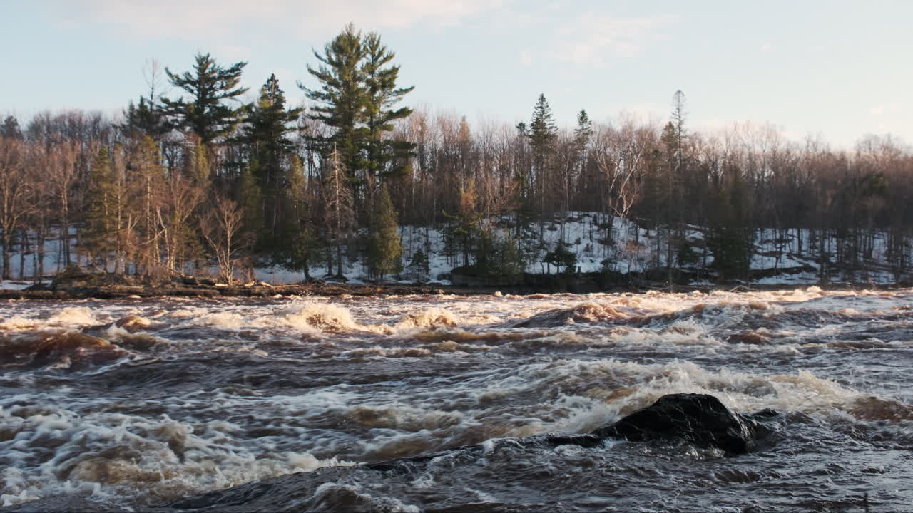 Lämmin iltahämärän hehku Pohjois-Minnesotan nopeasti virtaavan joen kuohuvilla koskilla