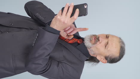 video vertical de video de un viejo hombre de negocios haciendo una videollamada por teléfono.