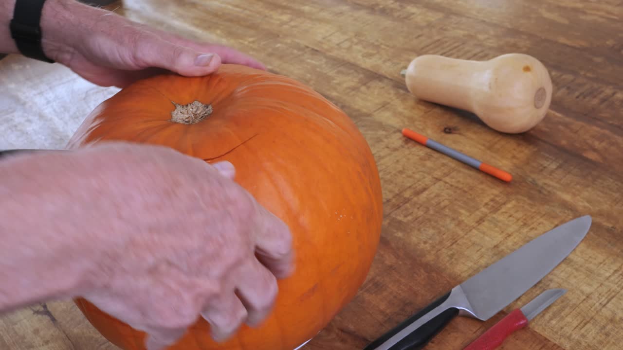 Person cutting pumpkin into jack-o’-lantern