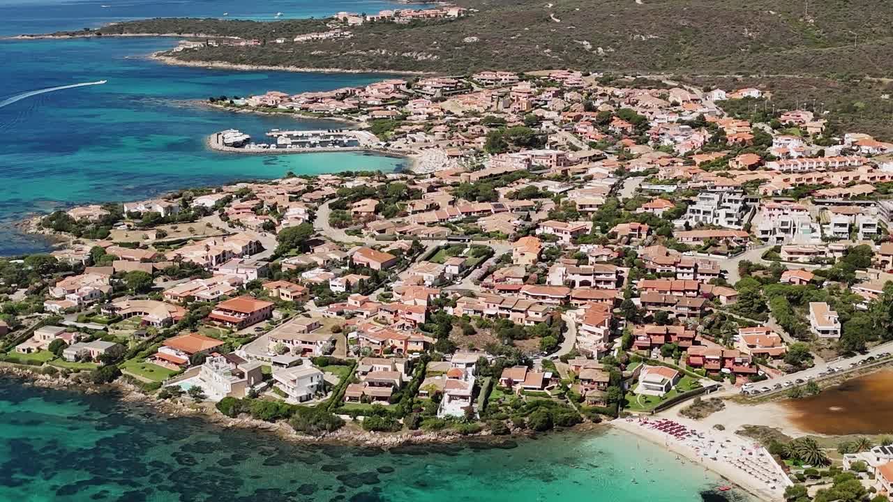 Berrak suları ve kumlu plajıyla Sardinya'daki bir sahil kasabasının görünümü