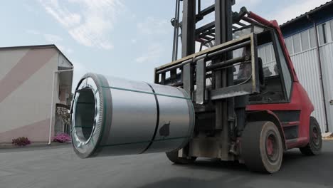 forklift driver loads rolls of steel sheet. industrial warehouse with rolls of steel sheet