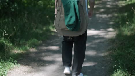 young man walking with guitar on street near forest