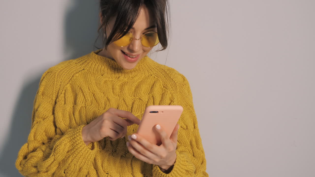 mujer usando el teléfono en suéter amarillo