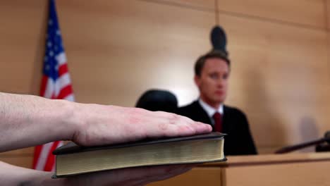 judge looking at the witness swearing on bible