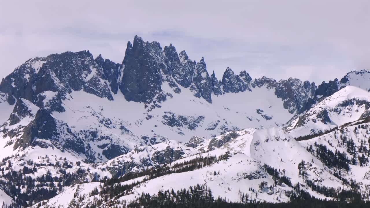 Minarets mountain range jagged towering peaks vista point panoramic landscape Mammoth Mountain ski resort aerial drone California winter spring sunny blue sky morning Inyo National Forest parallax