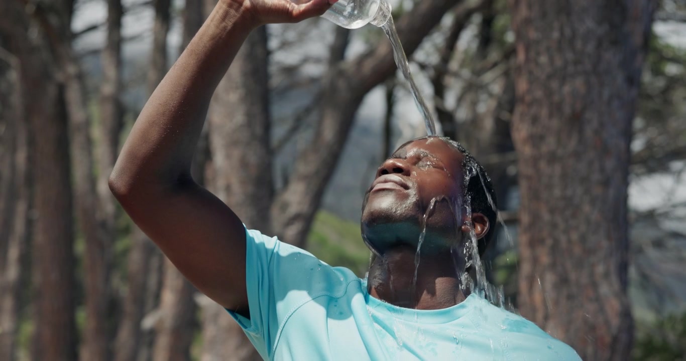 Athletic Man Pouring Water Over His Face in Forest