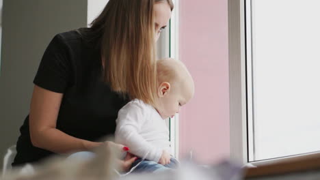 Mutter-Mit-Baby-Sitzt-Am-Fenster-Und-Spielt