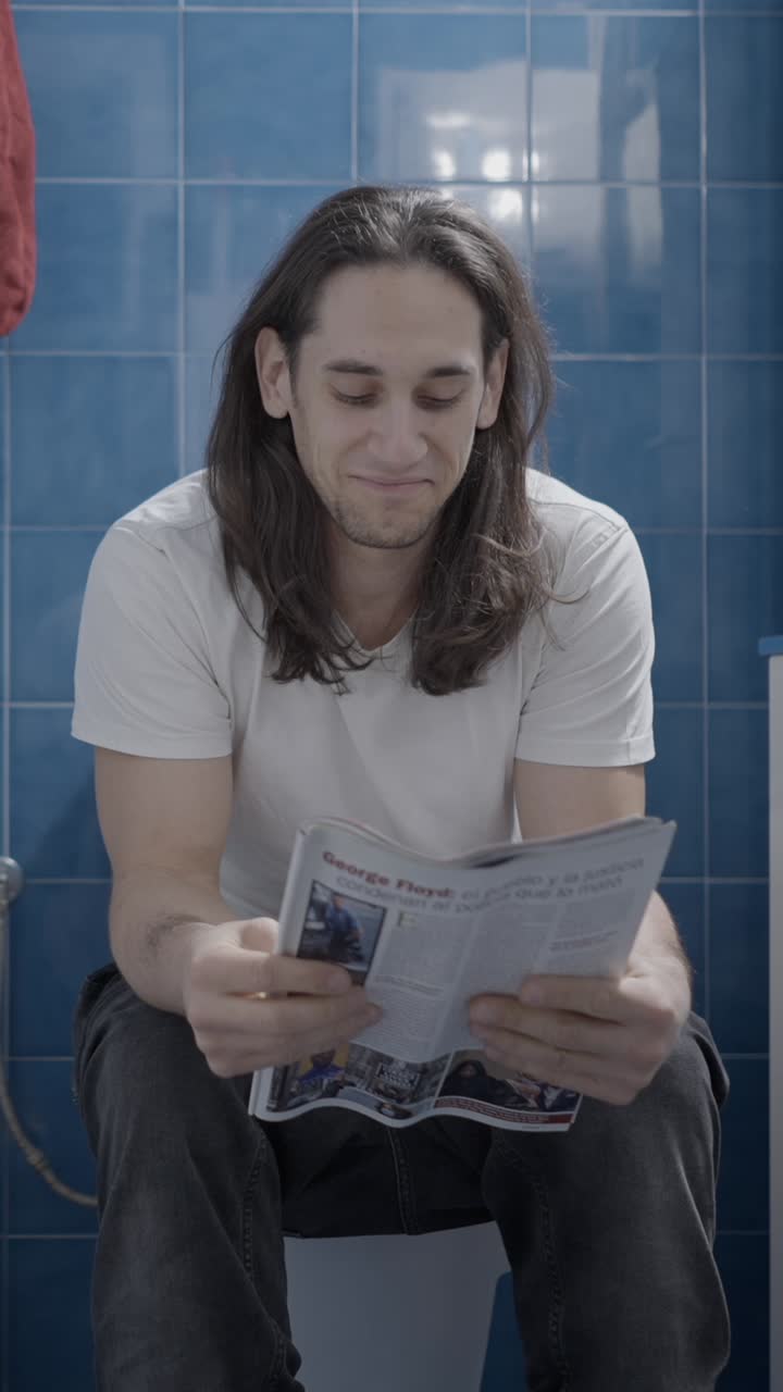 Man reading a newspaper on the toilet