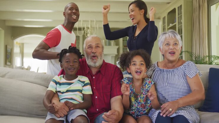 Three generation family cheering while watching TV at home
