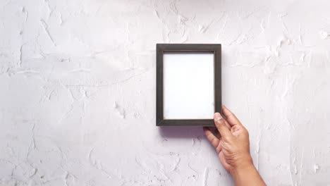 hand holding a blank rustic picture frame on white background