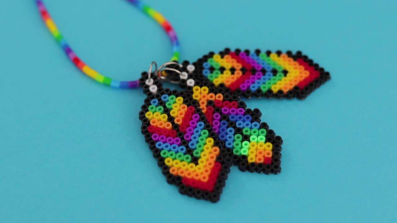 collar de cuentas de colores en forma de plumas sobre fondo azul, artesanía hecha a mano vibrante