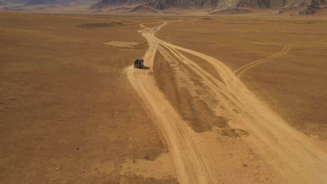 몽골 낮에 산을 향해 먼지 도로에서 대초원을 운전하는 밴의 공중 돌리