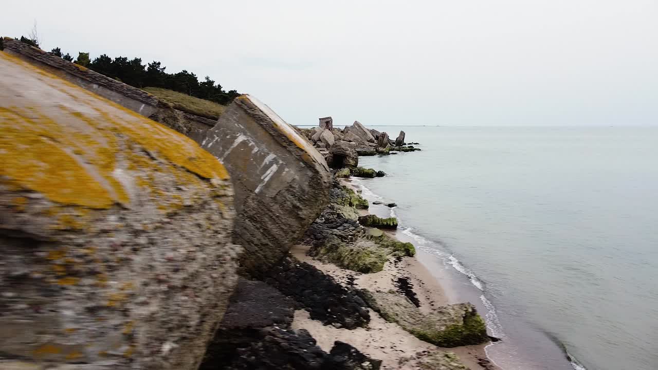 vista aérea del edificio de fortificación costero abandonado en los fuertes del norte de karosta en la playa del mar báltico en liepaja en un día nublado de primavera, tiro de drones moviéndose a la izquierda