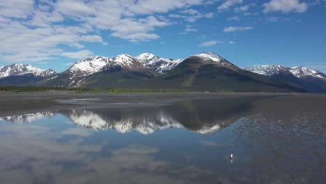 el avión no tripulado se eleva sobre las brillantes aguas del brazo de turnagain en alaska con majestuosos picos nevados de las montañas chugach en la península de kenai en el fondo
