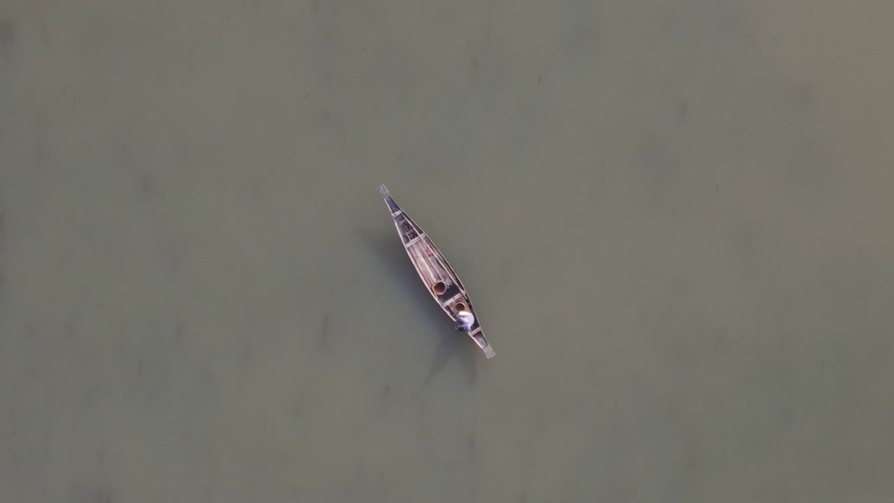 pescador pescando en un bote de madera en un río poco profundo