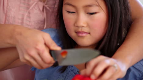 hija cortando un pimienta roja con su madre