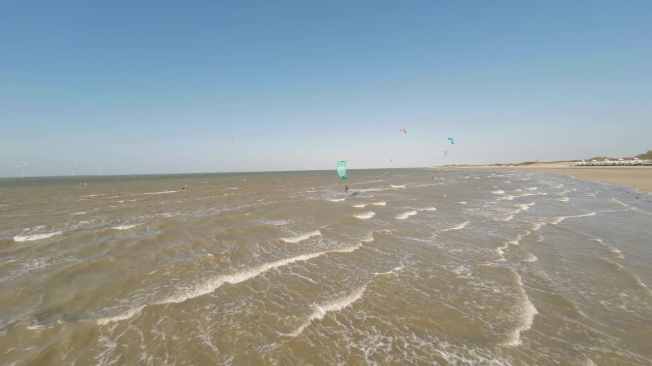 Aerial drone tracking shot of male kite surfer riding murky waves in strong wind